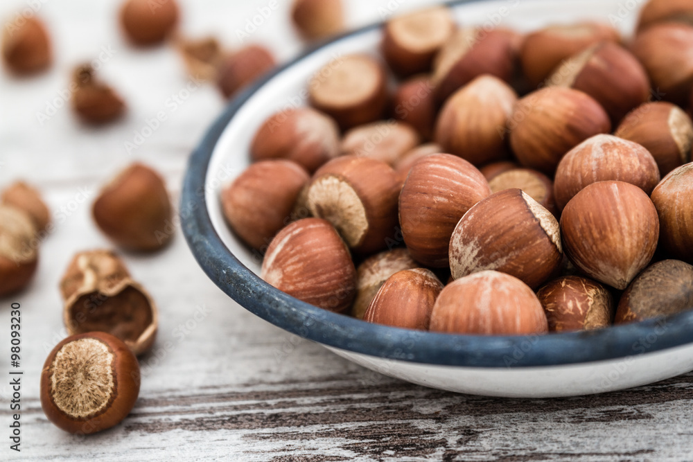 Hazelnuts in Enamel Bowl on White Wooden Table