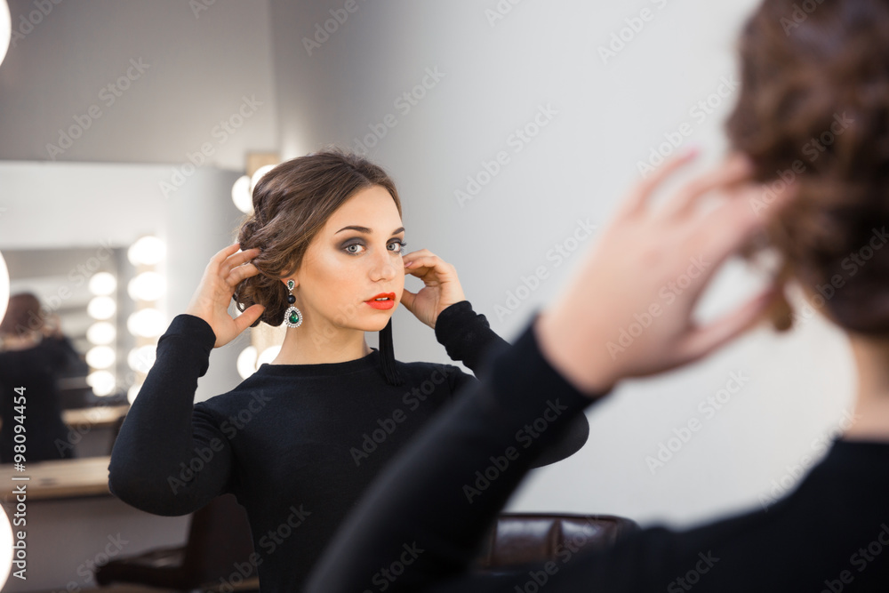 Woman looking at her reflection in the mirror Woman looking at her reflection in the mirror