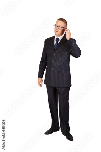 Businessman with serious face in suit and eyeglasses speaking on the cellphone, full length portrait isolated over white background