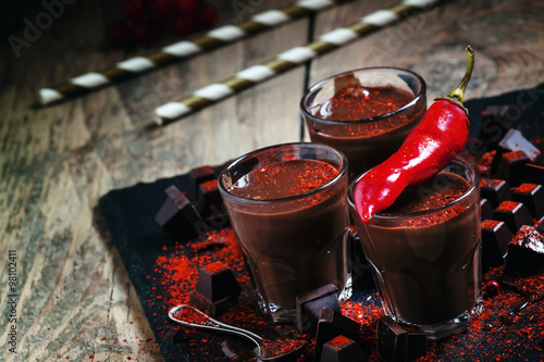 Hot spicy chocolate with red chili pepper on a dark background,