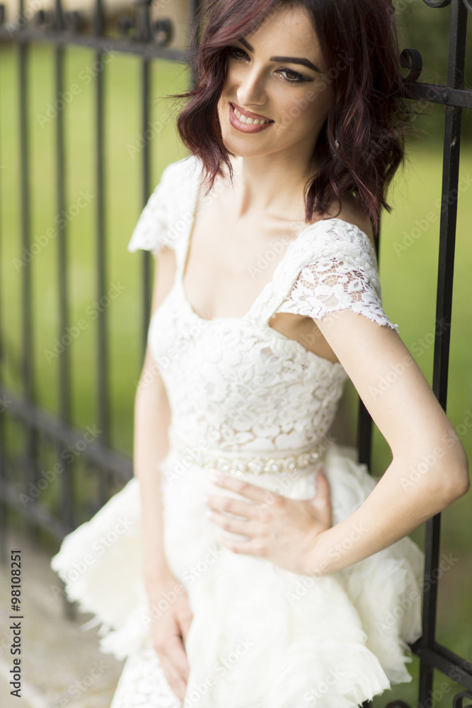 Naklejka premium Young woman in white drress by the fence