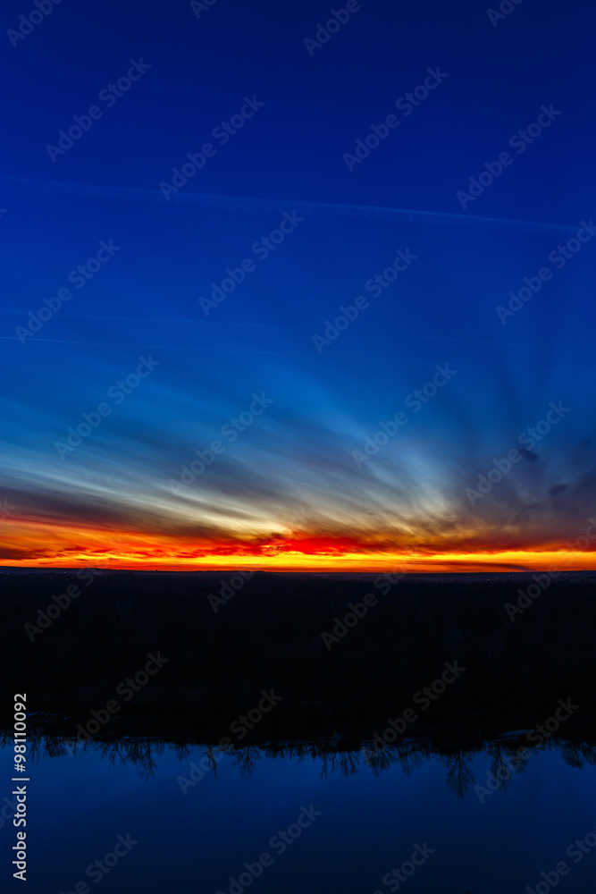 Fototapeta premium Sunset on the background of the smooth surface of the river.