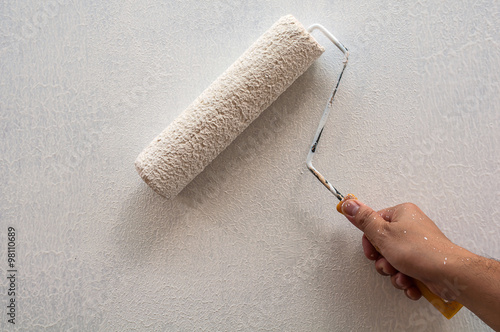 Hand holding rolling paint brush, wall painting