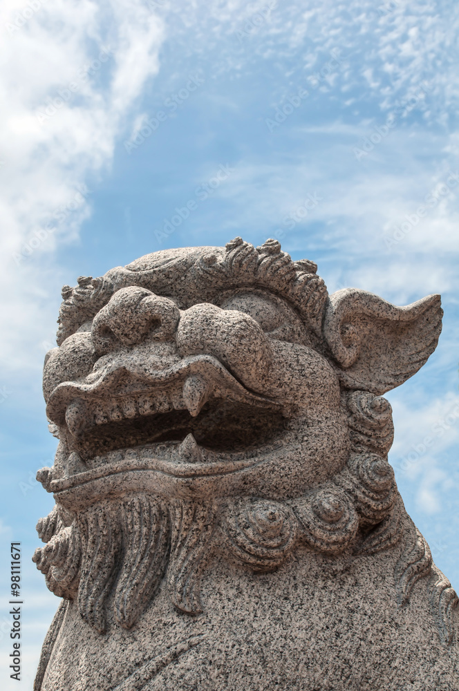 Chinese stone lion over blue sky background