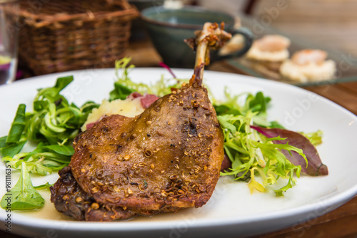 Dish with a roasted duck leg and green salad