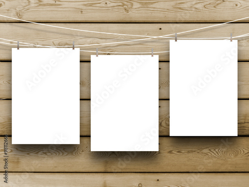 Three paper sheet frames hung by pegs on brown wooden boards background