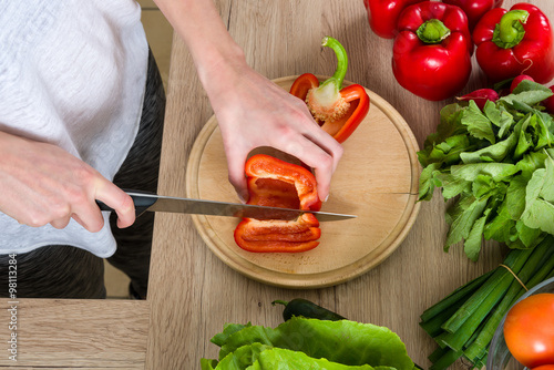 Woman in gym suite cutting vegetables in the kitchen, bird view photo