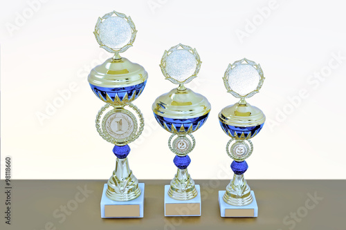Three metal cups of gold color with blue details © FedotovAnatoly