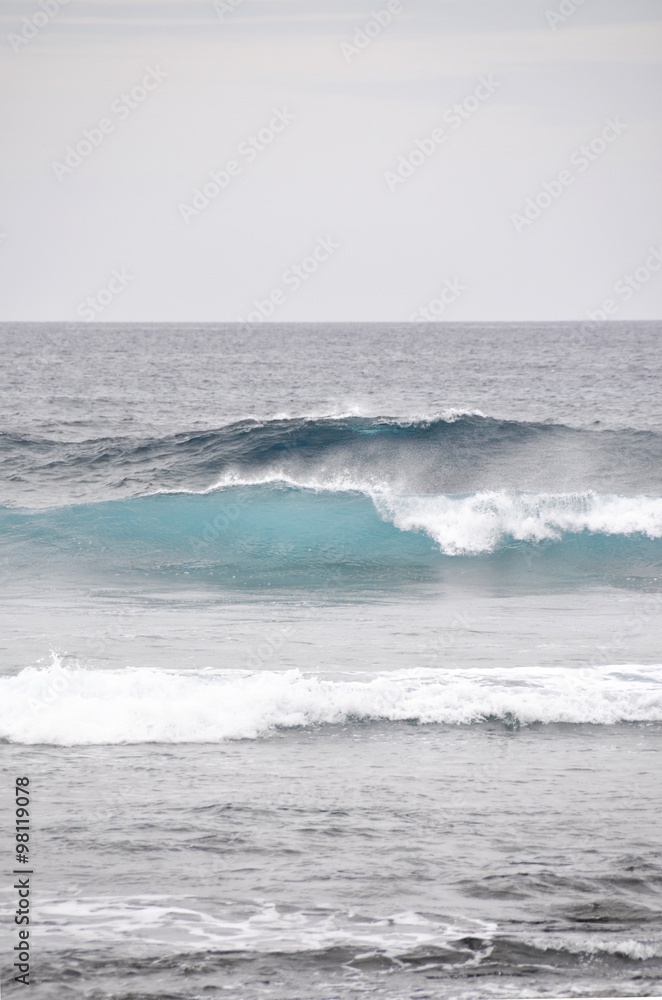 Blue wave rolls towards a beach