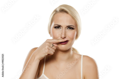 A woman holds a finger under the nose because of the smell