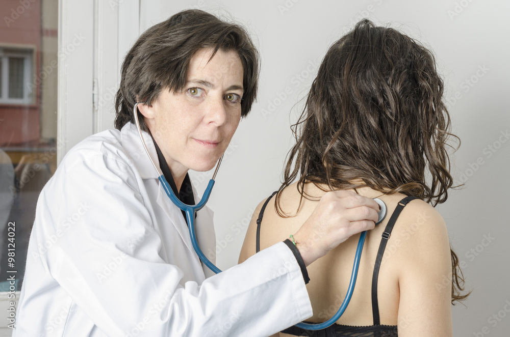 Doctor female auscultating young patient by stethoscope. Doctor female auscultating young patient by stethoscope.