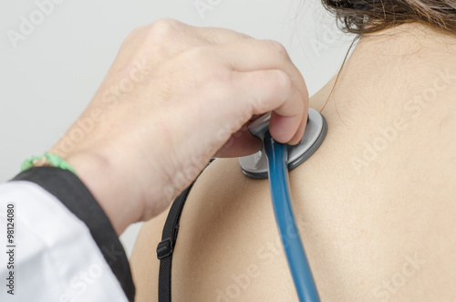 Doctor auscultating young patient by stethoscope.