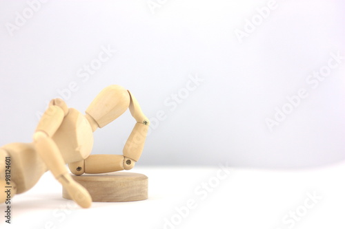 Wooden man thinking while lying with a white background. photo