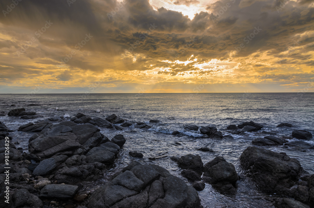 Dramatic sunset at the ocean with boulder rocks Dramatic sunset at the ocean with boulder rocks