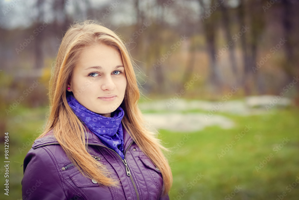 Beautiful girl in purple jacket having a stroll in park 