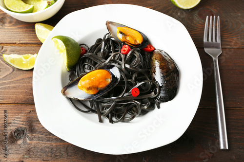 Cooked pasta, mussel and lime on brown wooden background © Africa Studio