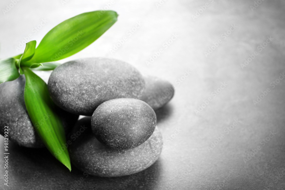 Hot spa stones with bamboo on grey background, close-up Hot spa stones with bamboo on grey background, close-up