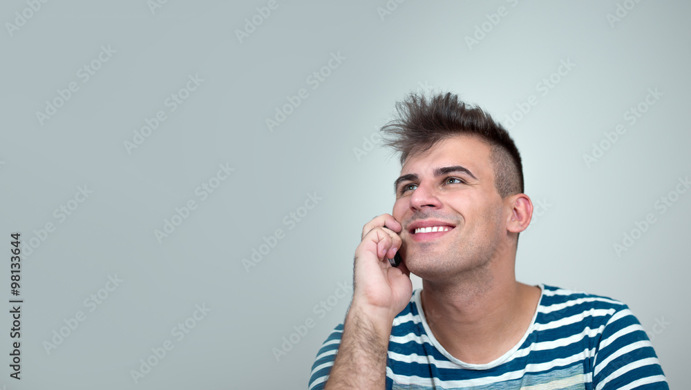 casual young man talking on the phone and smiling casual young man talking on the phone and smiling