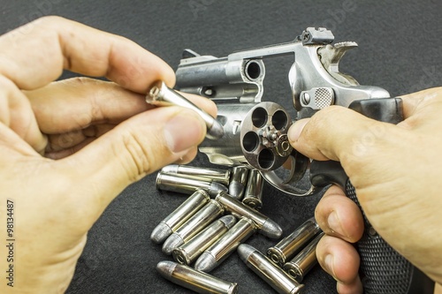 The .38mm and 9mm. bullet on hand reloading to a Revolver hand gun on black background. - weapon  photo