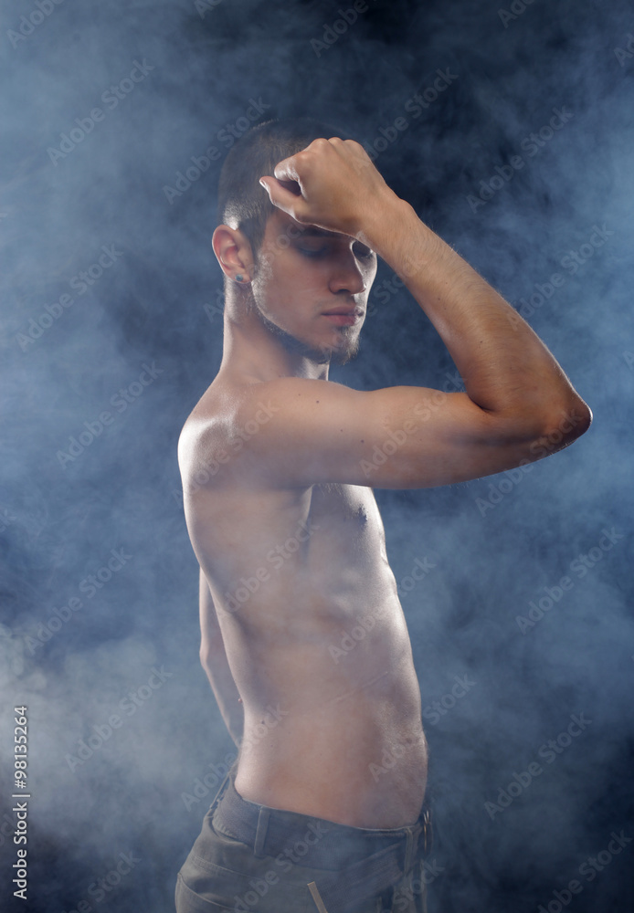 Portrait of a muscular male model against dark background with Portrait of a muscular male model against dark background with