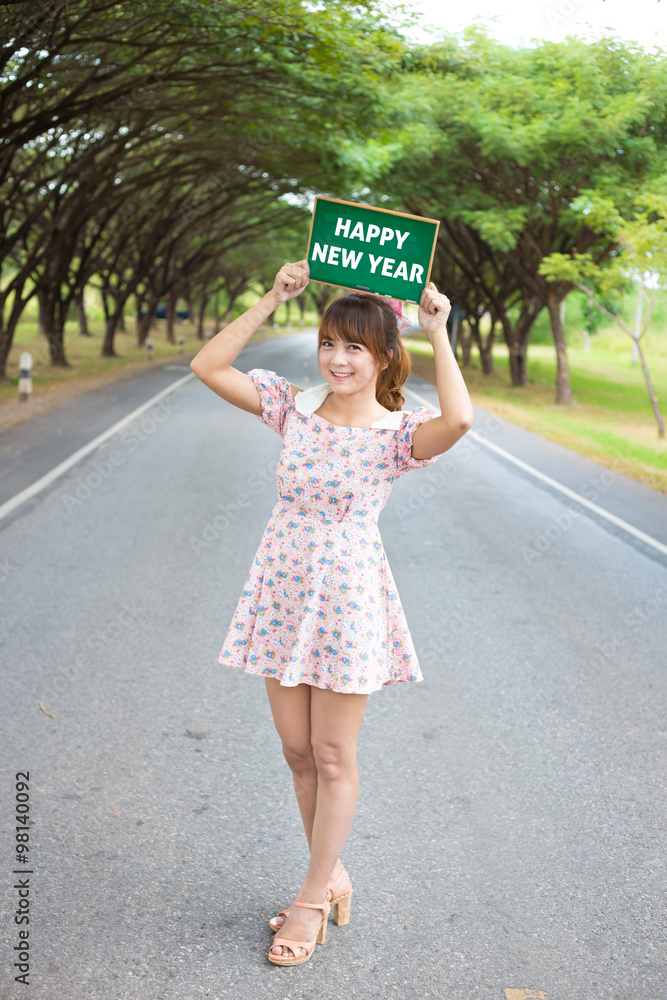 Φωτογραφία Cute woman hand holding green board sign with text  happy new year on road and