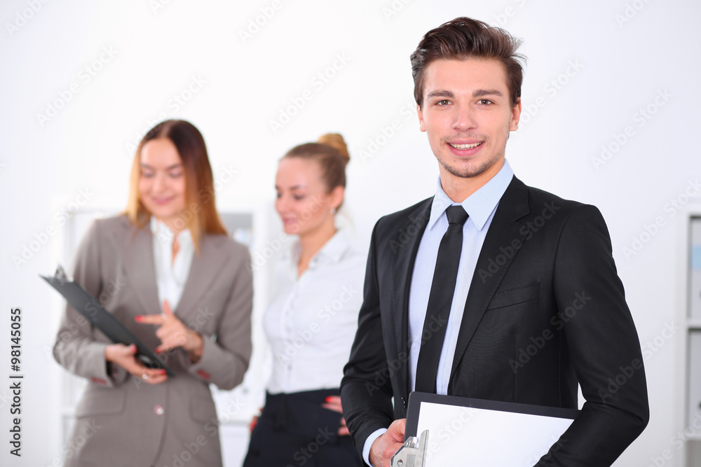 Cheerful business man in office with colleagues in the background, sturt up team Cheerful business man in office with colleagues in the background, sturt up team