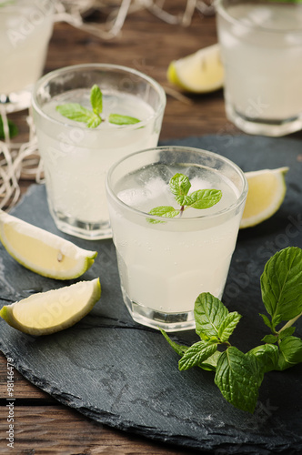 Fresh cocktail with lemon, ice and mint on the vintage table