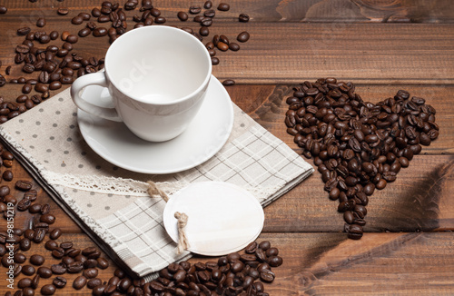White cup and coffee grains on a wooden surface