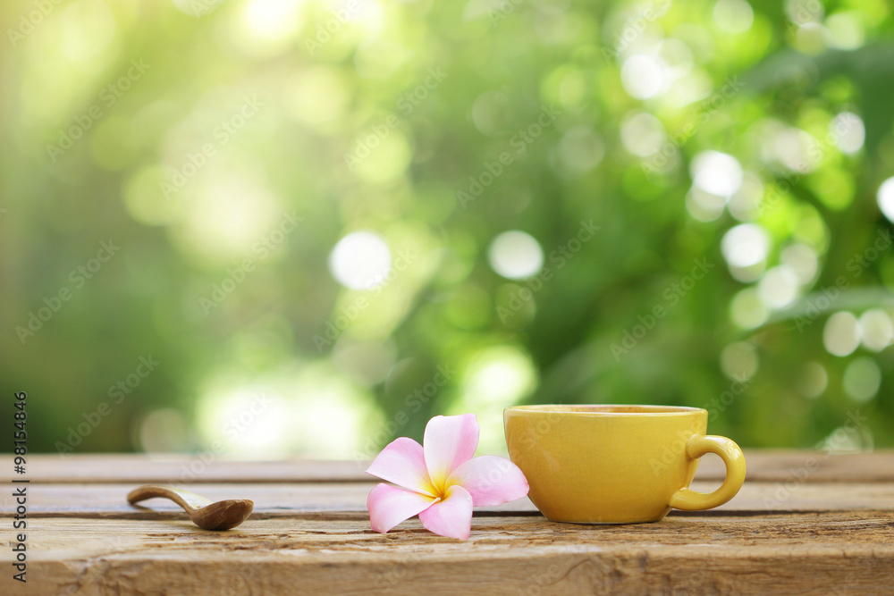 yellow coffee cup with flower and wooden spoon on wooden table yellow coffee cup with flower and wooden spoon on wooden table