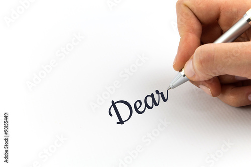 Hand writing "Dear"  on white sheet of paper.