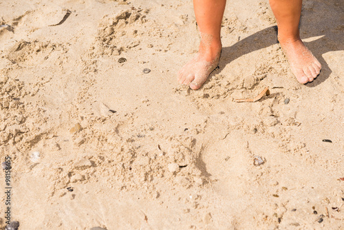 close-up of small feet on the sand in a sunny day