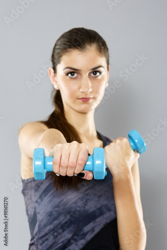 sporty woman do her workout with dumbbells, isolated on gray bac