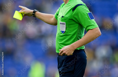 Arbitro de futbol sacando tarjeta amarilla