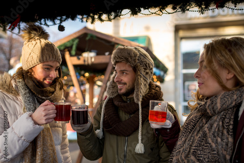 Couple and friend, Friends on a german  Christmas market enjoying traditional mullet wine and talk to each other
