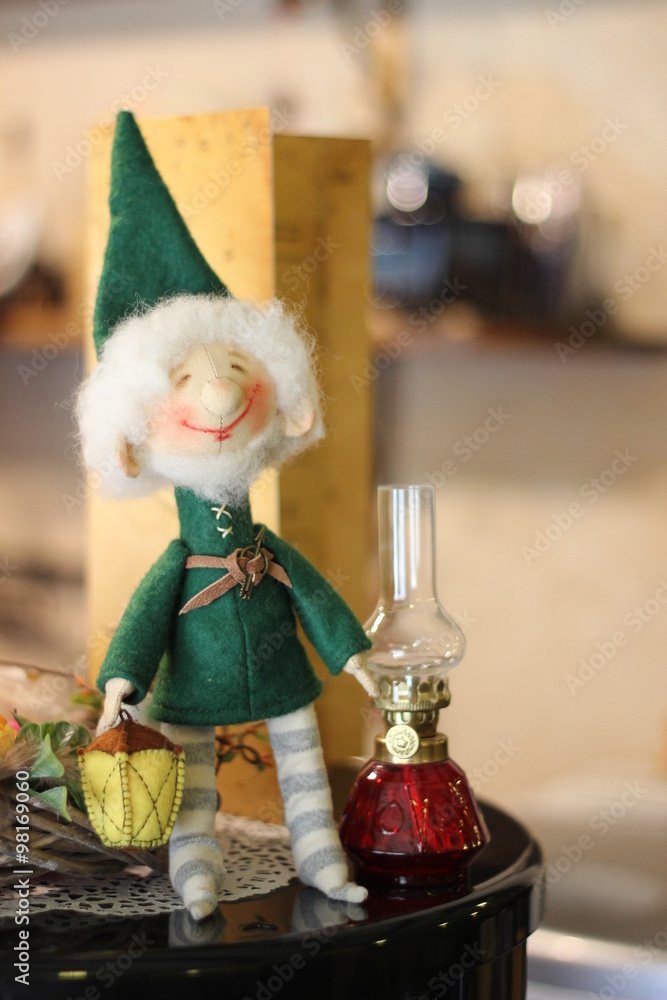 Textile doll gnome in a green jacket and a flashlight in striped socks