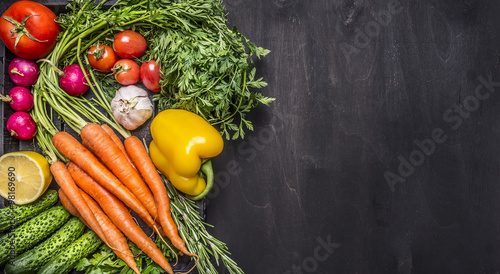 Colorful various organic farm vegetables carrots cherry tomatoes, garlic, cucumber, lemon, pepper, radish, wooden spoon salt pepper colored, oil wooden rustic background top view  border, place text