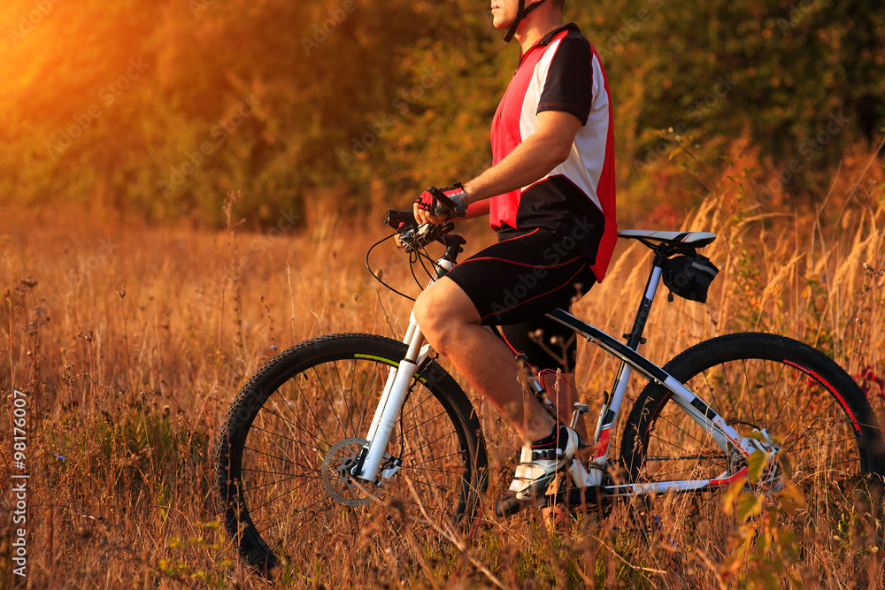 cyclist man cycling on a rural road during sunset cyclist man cycling on a rural road during sunset