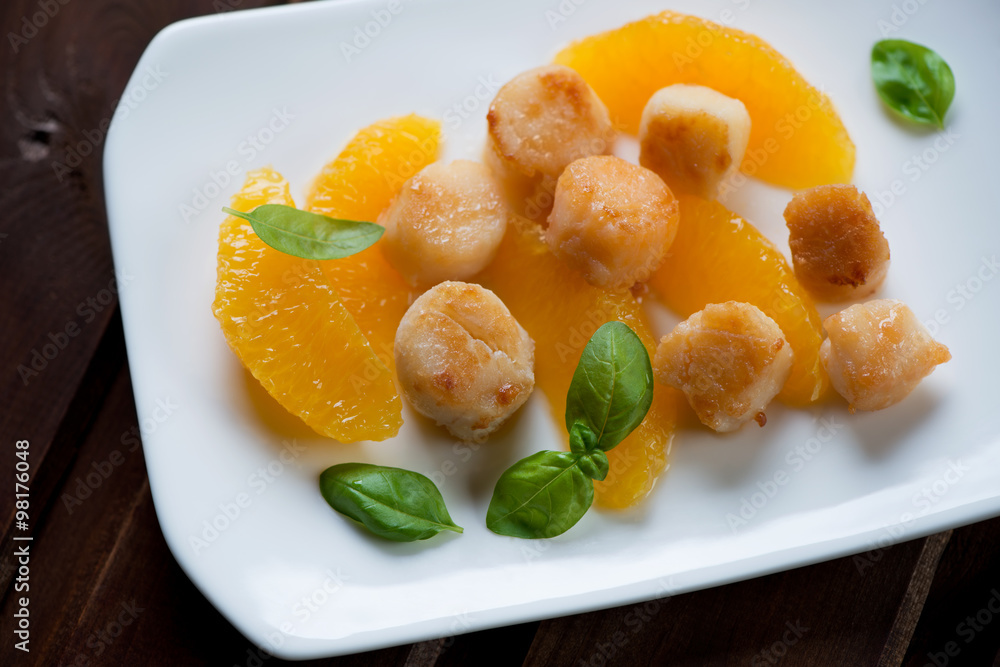 Roasted sea scallops served with orange filet and basil, closeup Roasted sea scallops served with orange filet and basil, closeup