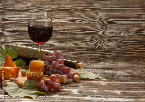 Fototapeta Naklejka Na Ścianę i Meble -  Glass of red wine, honeycomb, grapes on a wooden background. Selective focus.