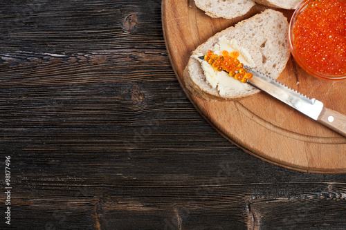 Bread and red caviar on a wooden background.