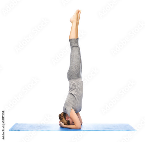 Fototapeta woman making yoga in headstand pose on mat