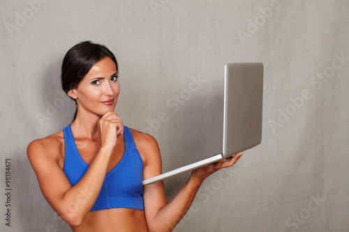 Good-looking lady holding laptop with hand on chin