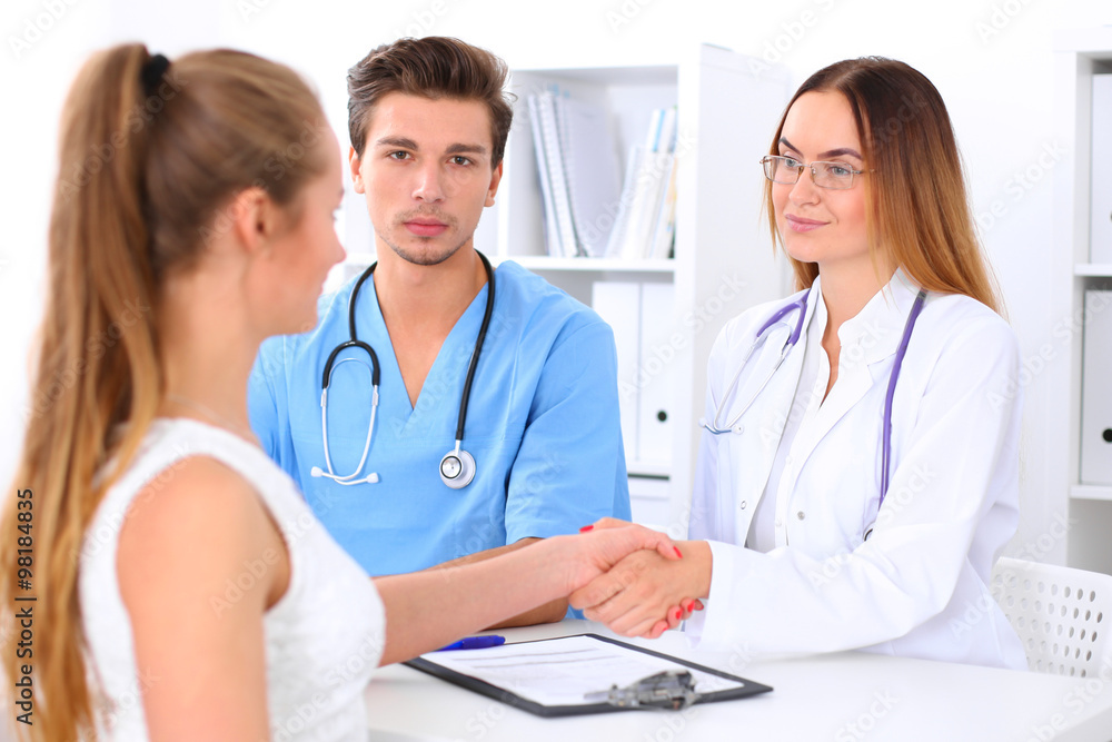 Male doctor and female patient shaking hands. Partnership, trust and medical ethics concept Male doctor and female patient shaking hands. Partnership, trust and medical ethics concept