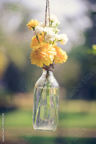 The marigold flowers in a glass bottle hanging