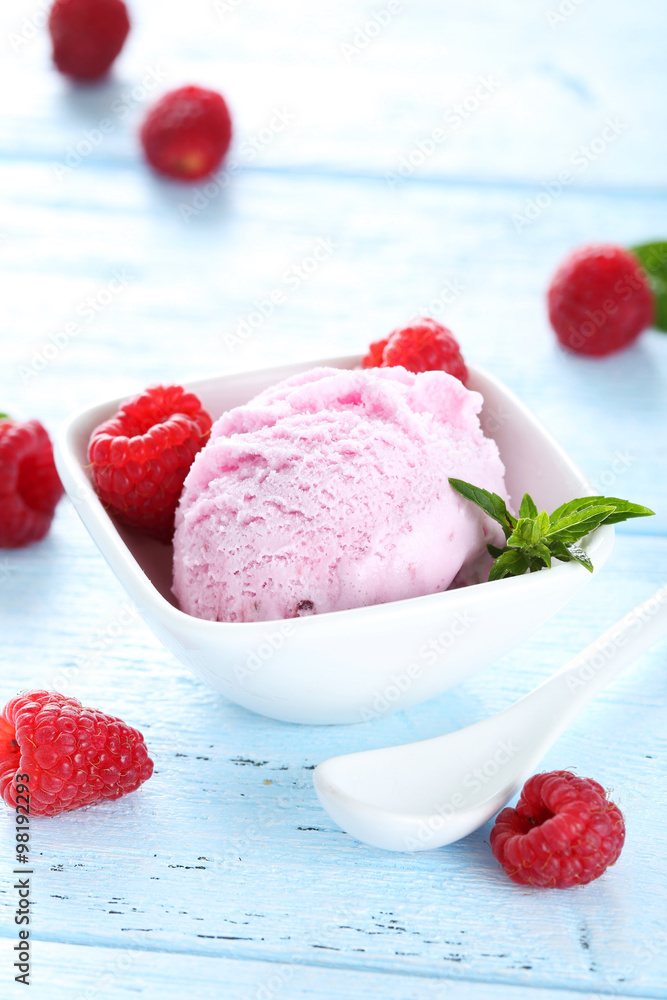 Ice cream in bowl with raspberries on blue wooden background Ice cream in bowl with raspberries on blue wooden background