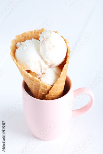 Waffle cone with white ice cream on wooden table