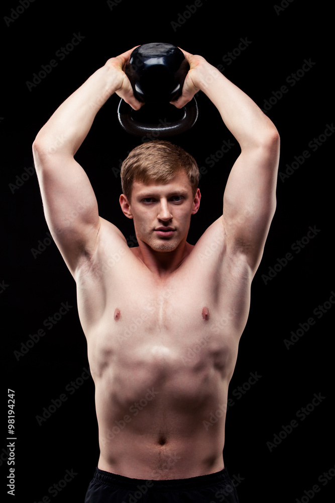 Handsome muscular guy with kettlebells isolated on black background Handsome muscular guy with kettlebells isolated on black background