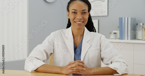 Canvas Print Black woman doctor sitting at desk smiling