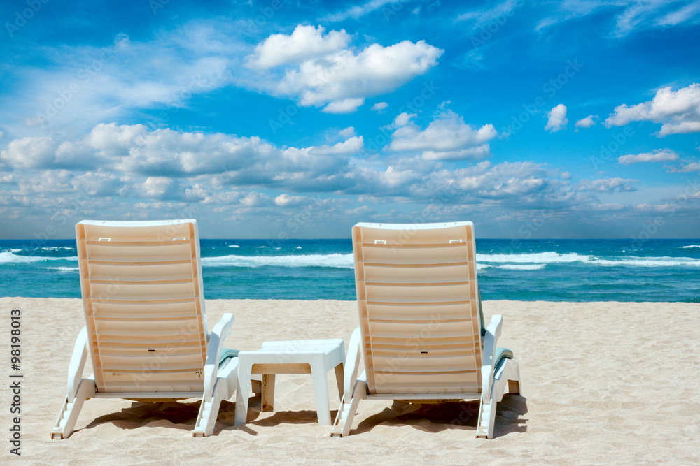 Two sun beach chairs on coast near ocean