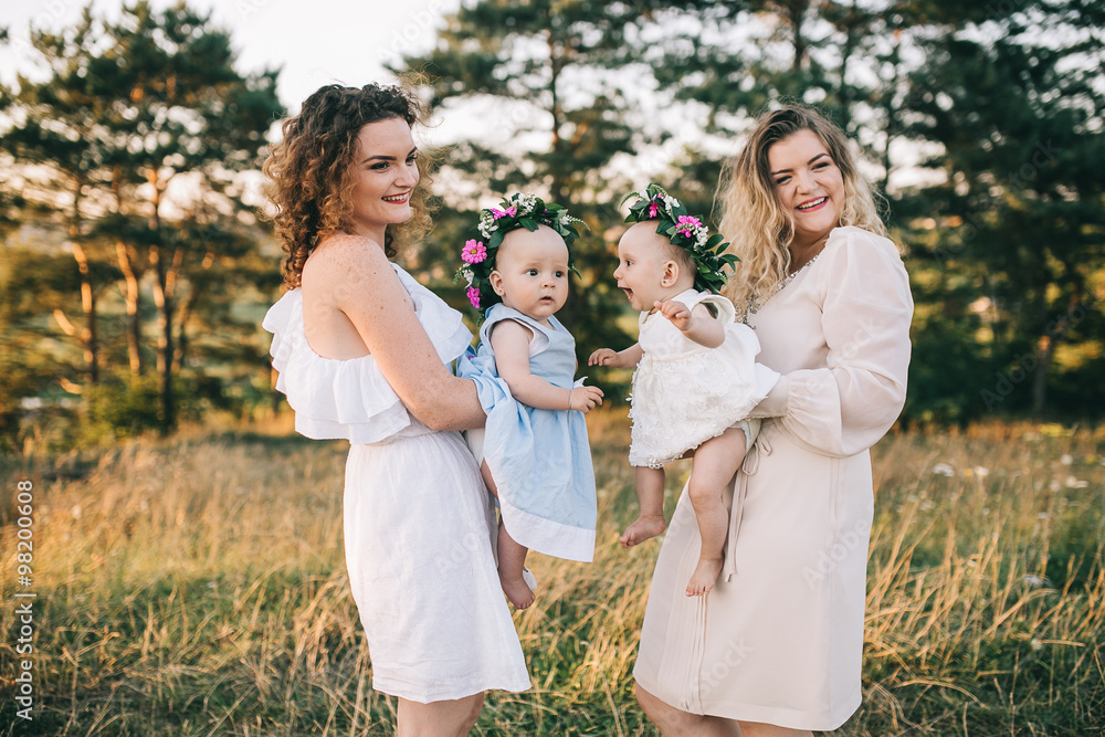 Two mothers and two daughters in summer whisk at sunset